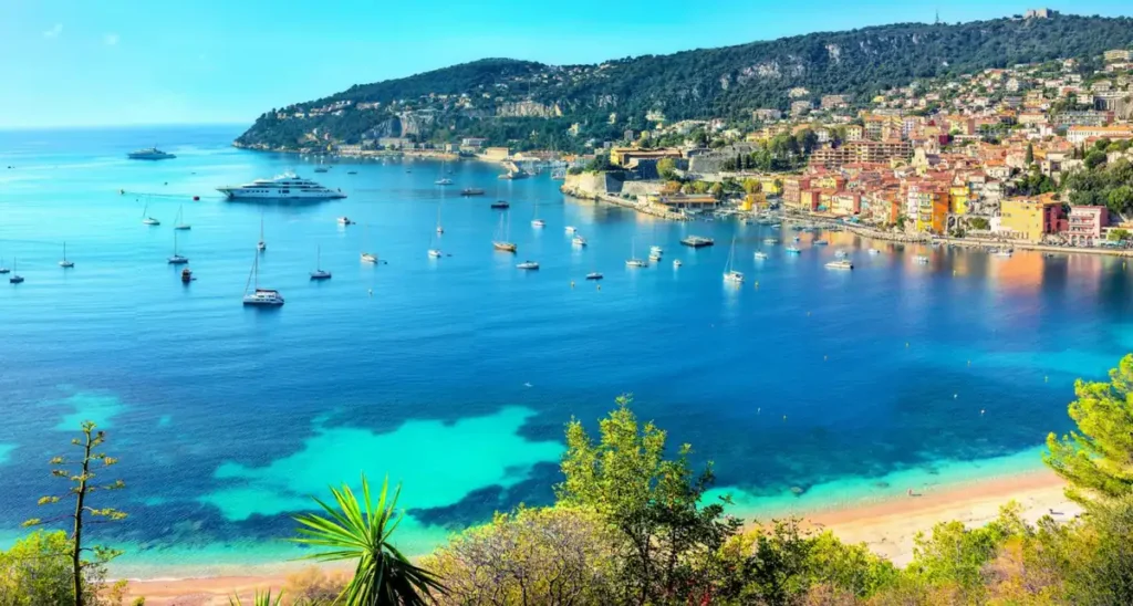 Baía de Villefranche-sur-Mer, um dos cenários mais conhecidos da Riviera Francesa, situada entre Nice e Saint-Jean-Cap-Ferrat. A paisagem reúne praias mediterrâneas, águas azul-turquesa, veleiros, iates e construções coloridas nas encostas, tornando Villefranche-sur-Mer um destino popular para passeios de barco e viagens pela Côte d’Azur.