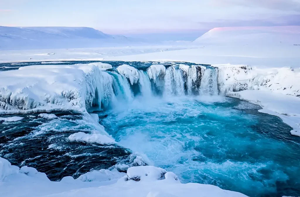 Cachoeira Goðafoss, conhecida como Cachoeira dos Deuses, no norte da Islândia, próxima à cidade de Akureyri. Durante o inverno, suas águas azul-turquesa contrastam com gigantescas formações de gelo, neve e paisagens vulcânicas, criando um dos cenários naturais mais impressionantes da rota Diamond Circle.