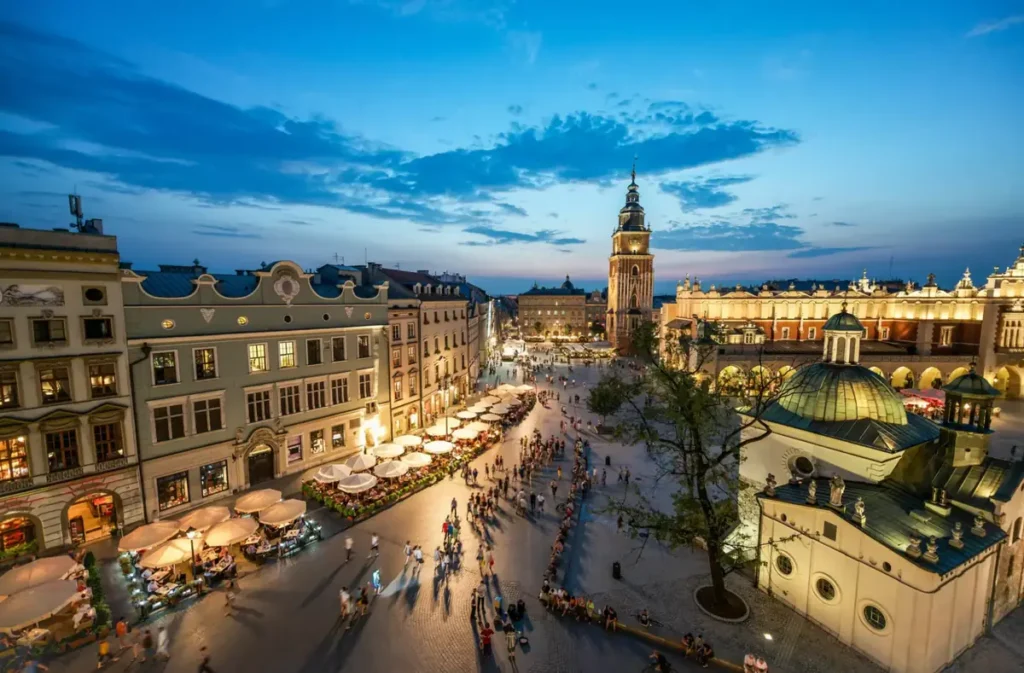 Praça do Mercado de Cracóvia, conhecida como Rynek Główny, durante o entardecer. Localizada no coração do centro histórico da cidade, a praça reúne construções medievais, cafés, restaurantes e monumentos emblemáticos, sendo uma das principais atrações turísticas de Cracóvia, na Polônia.