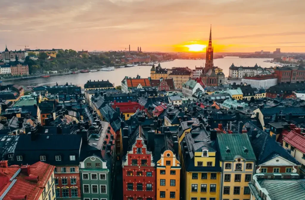 Gamla Stan, o centro histórico de Estocolmo, fotografado ao pôr do sol. A paisagem reúne construções medievais, fachadas coloridas, a Igreja de Riddarholmen e os canais que cercam as ilhas da capital sueca. Uma das regiões mais visitadas de Stockholm, famosa por suas ruas históricas e vistas panorâmicas.