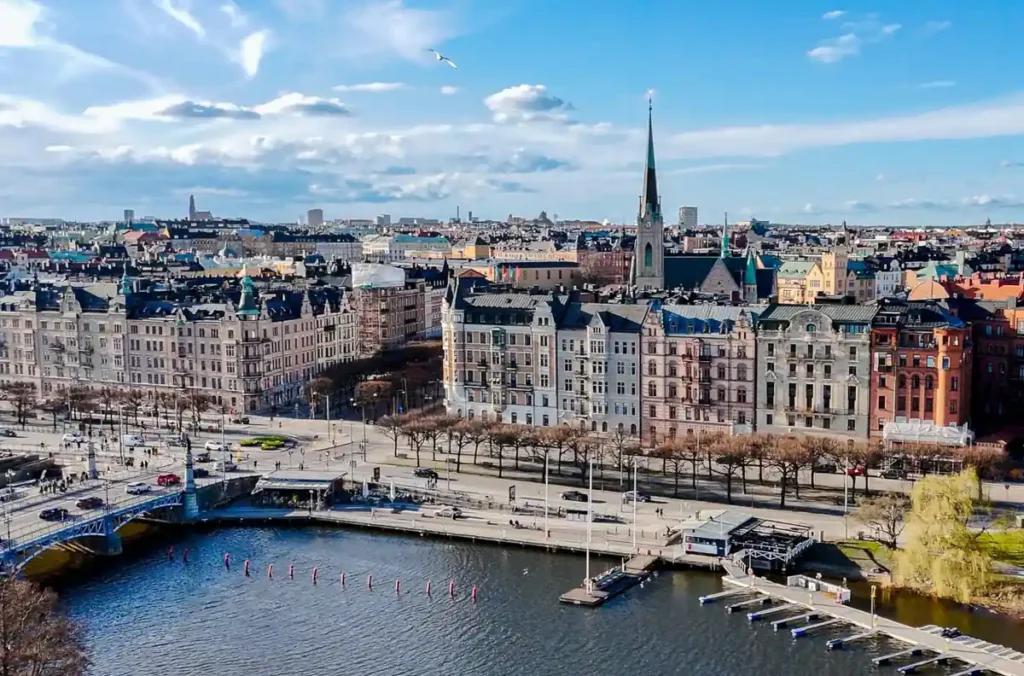 Vista aérea de Estocolmo, na Suécia, destacando a arquitetura histórica, os canais, as pontes e os edifícios elegantes da capital sueca. Construída sobre diversas ilhas conectadas por pontes, Stockholm é conhecida por suas paisagens urbanas à beira da água, patrimônio arquitetônico e atmosfera escandinava.