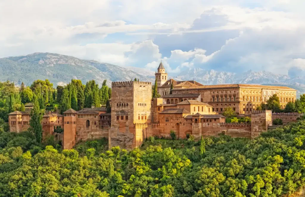 Alhambra de Granada, um dos monumentos mais emblemáticos da Espanha e Patrimônio Mundial da UNESCO. A fortaleza e seus palácios históricos destacam-se entre jardins verdes e as montanhas da Sierra Nevada, formando uma das paisagens mais famosas da Andaluzia.