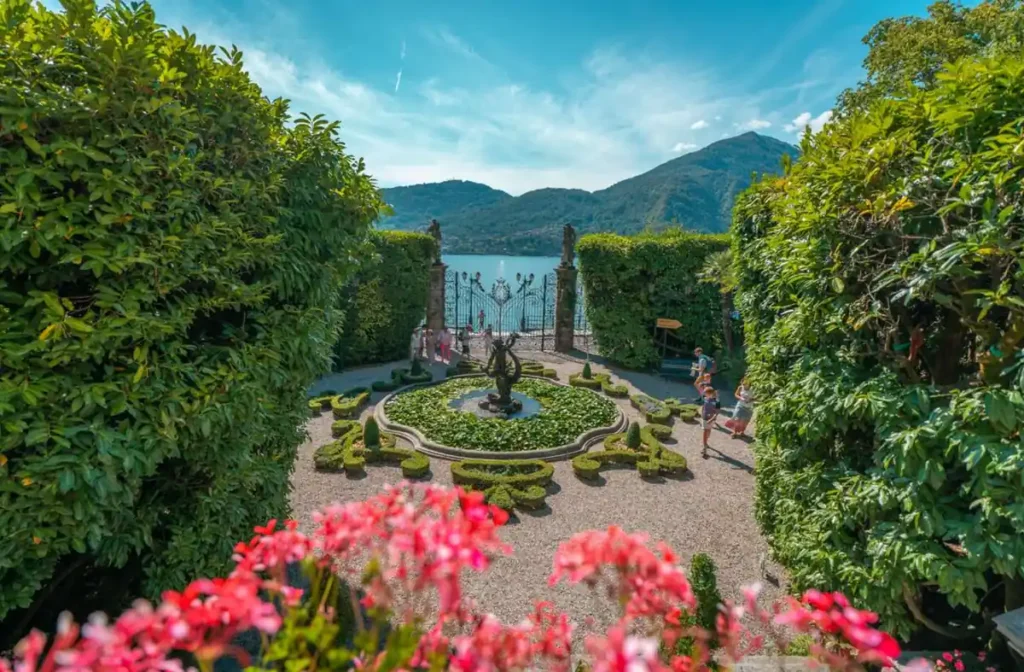 Jardim histórico às margens do Lago di Como, na Itália, com fonte ornamental, esculturas e vegetação cuidadosamente cultivada. Os jardins das villas históricas estão entre as atrações mais conhecidas da região, combinando paisagismo clássico italiano e vistas panorâmicas das montanhas.