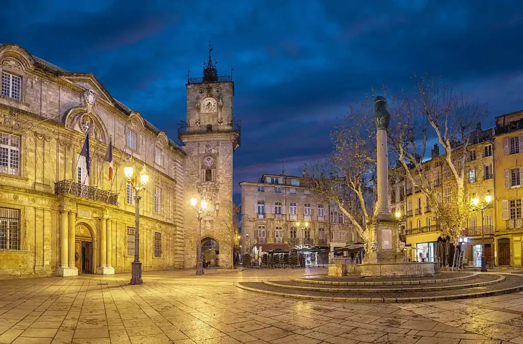 Place de l'Hôtel de Ville, no centro histórico de Aix-en-Provence, uma das cidades mais importantes da Provence, no sul da França. A praça reúne a arquitetura clássica da prefeitura, a histórica Tour de l'Horloge e edifícios provençais. Ao anoitecer, a iluminação amarelada destaca o patrimônio arquitetônico e a atmosfera das praças tradicionais francesas.