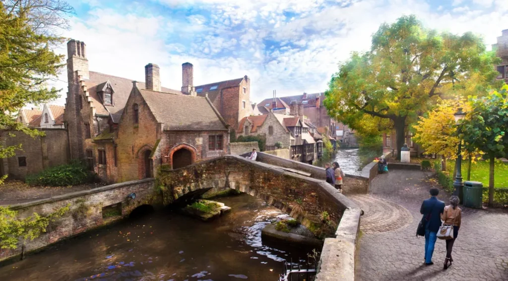 Vista da Ponte de São Bonifácio (Bonifaciusbrug), um dos lugares mais charmosos e fotografados de Bruges, na Bélgica. Localizada no coração do centro histórico, a pequena ponte de pedra atravessa um canal cercado por construções tradicionais de tijolos, fachadas medievais e árvores que emolduram a paisagem. A fotografia destaca a arquitetura histórica da cidade, os caminhos de paralelepípedos e a atmosfera tranquila que faz de Bruges um dos destinos mais românticos da Europa. Reconhecido como Patrimônio Mundial da UNESCO, o centro histórico de Bruges preserva canais, pontes e edifícios que testemunham sua importância comercial durante a Idade Média.