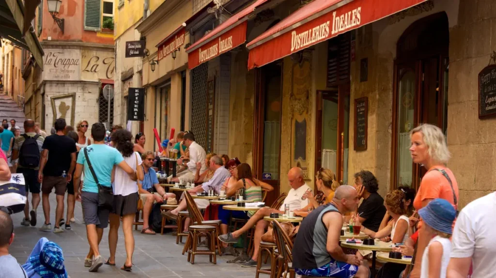 Restaurantes e cafés nas ruas históricas do Vieux Nice, a Cidade Velha de Nice, na Côte d’Azur, França. O bairro é conhecido por suas vielas estreitas, edifícios coloridos, mercados, bistrôs e gastronomia provençal, oferecendo uma experiência típica da cultura mediterrânea e da vida cotidiana na Riviera Francesa.