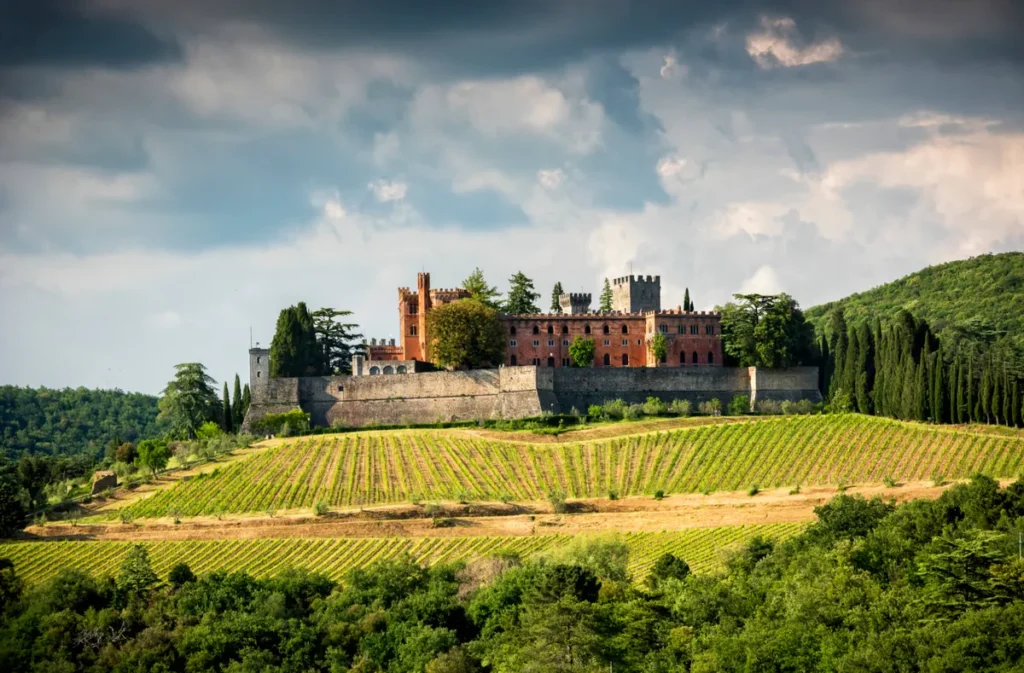 Castelo histórico cercado por vinhedos na Toscana, onde a arquitetura medieval se integra à paisagem vinícola da região.