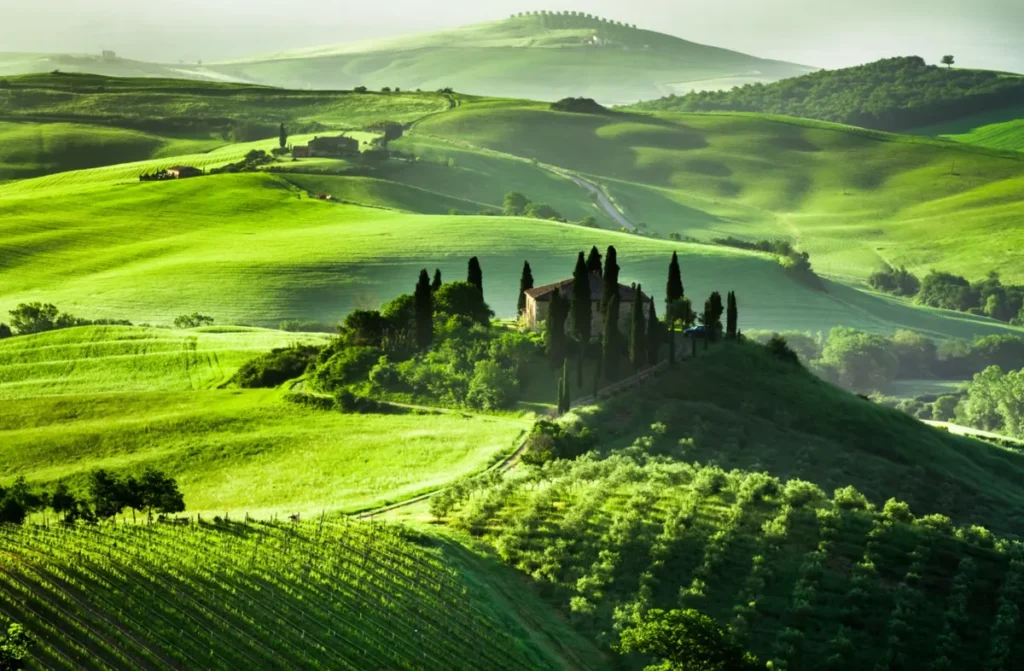 Paisagem típica da Toscana, com colinas suaves, campos verdes e ciprestes que caracterizam o interior da região.